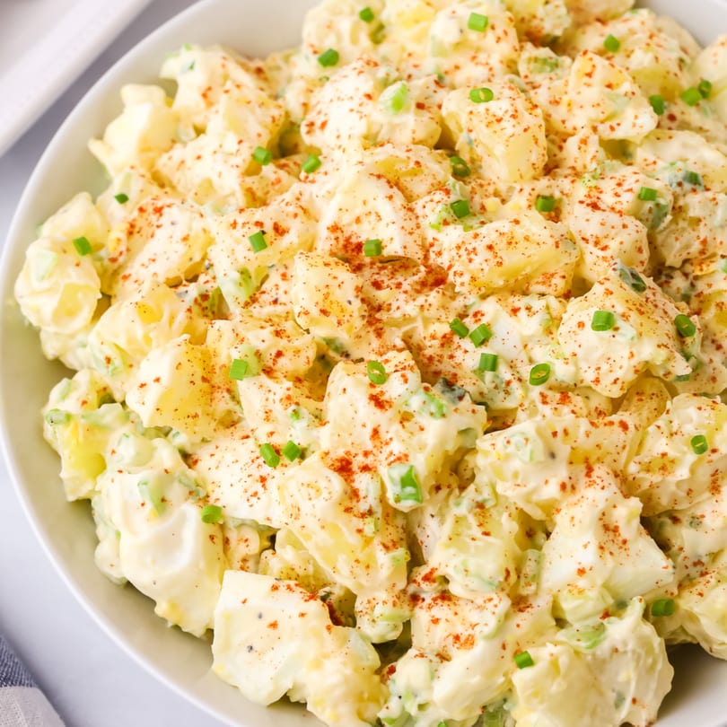 Creamy American potato salad with paprika and chives in a white bowl at The Potpourri House Restaurant.