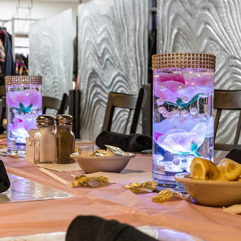 Table setting with illuminated floral centerpieces, salt and pepper shakers, and lemon wedges.
