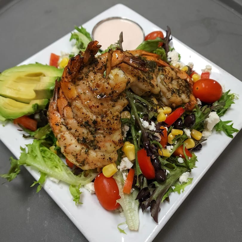 Grilled shrimp salad with avocado, cherry tomatoes, corn, black beans, and feta cheese.