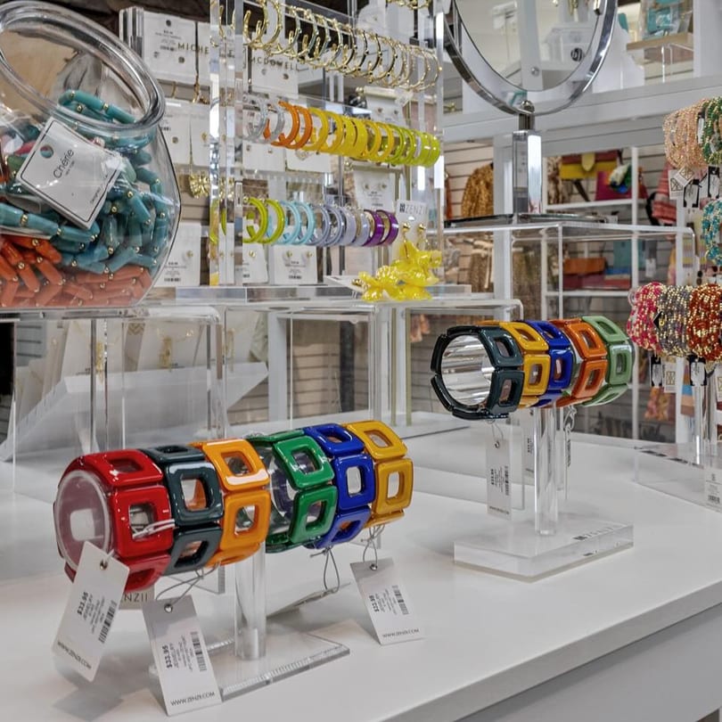 Colorful bracelets and earrings displayed on clear stands in a retail store.
