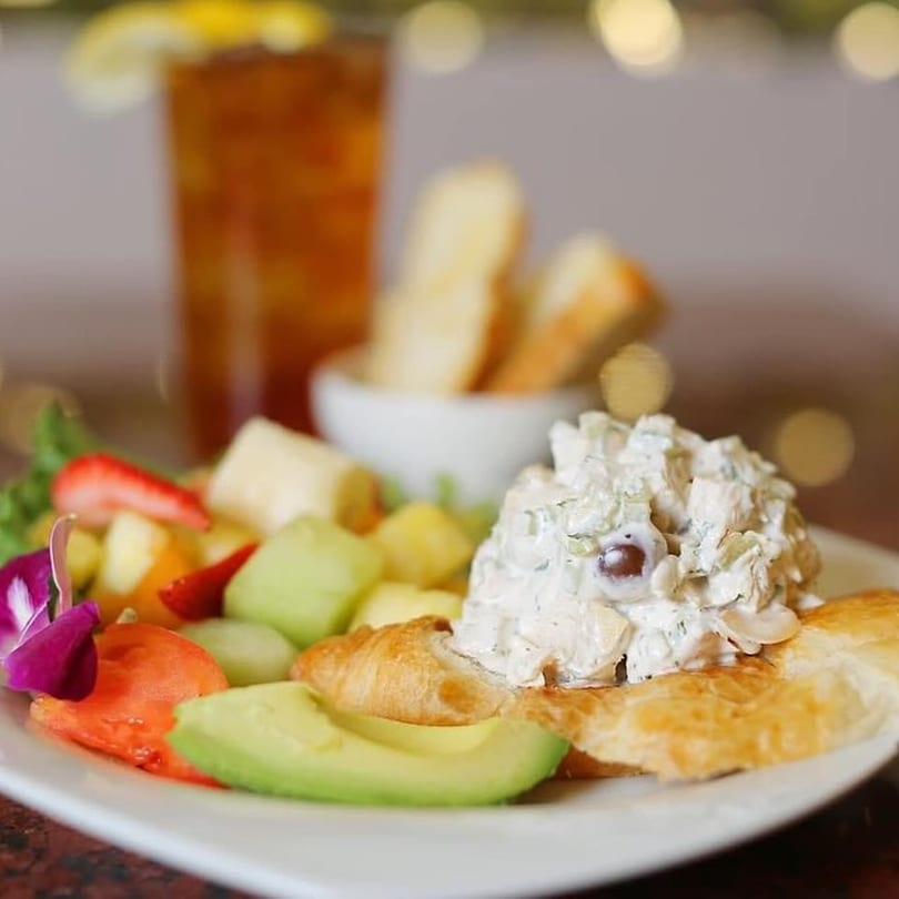 Chicken salad on a croissant with fruit, avocado, and iced tea at The Potpourri House.