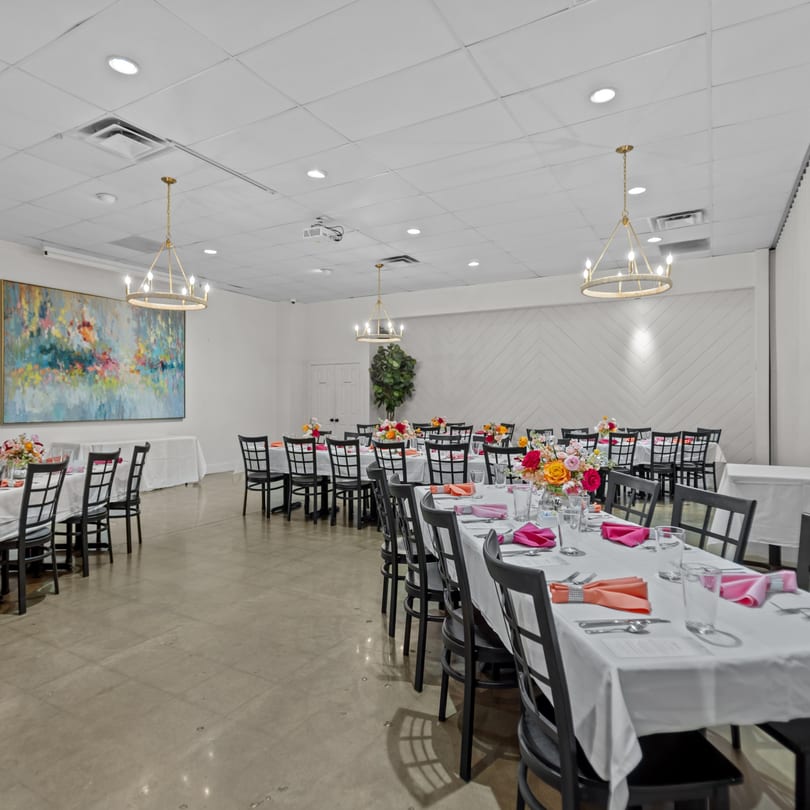 A large, brightly lit event room at The Potpourri House Restaurant with multiple tables set for dining.